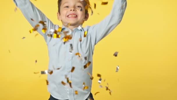 Gelukkig jongetje dat confetti gooit. Kind in blauw shirt en feestmuts. — Stockvideo