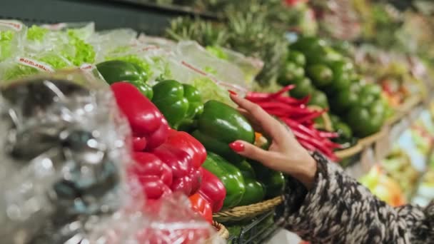 Woman buying green pepper in supermarket. Hand choosing organic vegetables — Stock Video