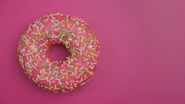 Delicioso donut doce girando em fundo rosa. Vista superior da fiação do donut — Vídeo de Stock