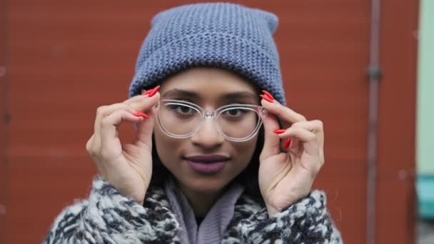 戴眼镜的千禧年女人看着相机笑着 头戴帽子 身穿外套 Uhd 4K地区美丽的混血妇女的特写 — 图库视频影像