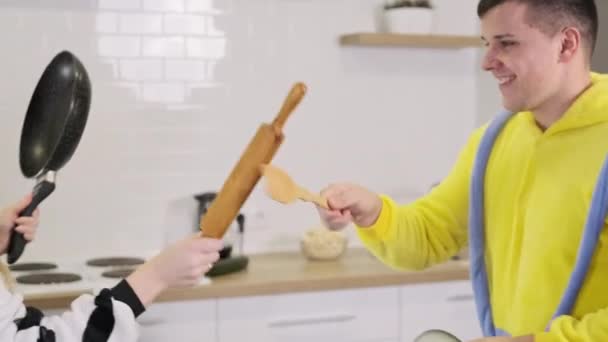 Couple en kigurumi ont combat drôle à l'intérieur. Combat de famille avec des outils de cuisine — Video