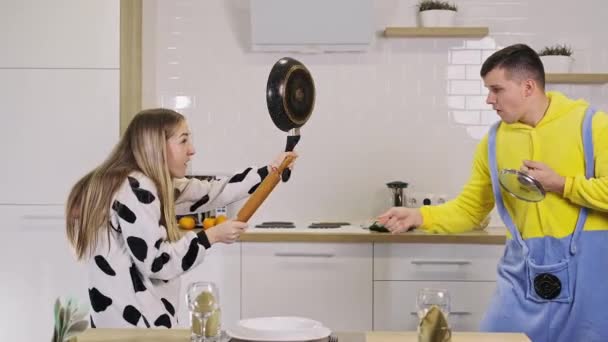 Couple heureux s'amuser dans la lutte de cuisine avec rouleau à pâtisserie et poêle à la maison . — Video