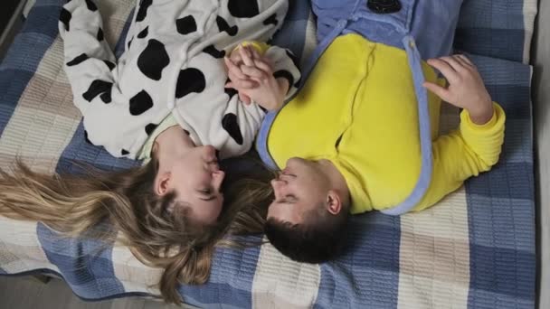 Happy young couple in funny pajamas cuddling together in bed. 4K, UHD — Stock Video