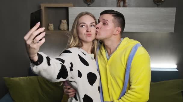 Joven pareja divertida en pijama tomando fotos selfie con cámara de teléfono inteligente — Vídeo de stock