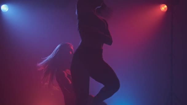 Seksuele silhouetten bij rode en blauwe spots. Dansen meisjes met sexy lichaam — Stockvideo