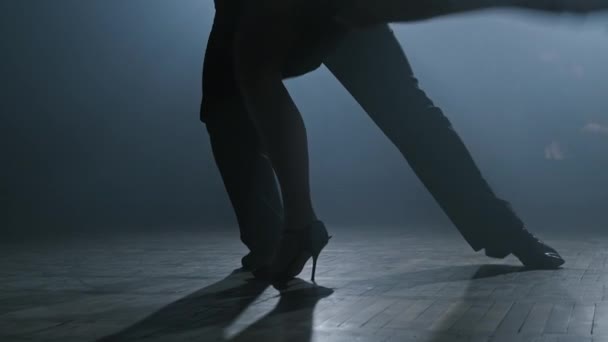 Ноги пары танцующих танго в темно-дымчатой студии в замедленной съемке в 4K, UHD — стоковое видео