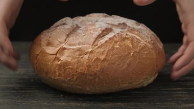 Pişirmek iştah açıcı bir somun ekmek. Fırıncı elleri ev yapımı ekmek kırıyor. Organik gıda konsepti. Lezzetli beyaz ekmek. 4K 'da yakın plan, UHD