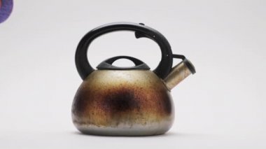 Beyaz arka planda metal çaydanlığı yıkayan turuncu lastik eldivenleri verin. Ev işleri.