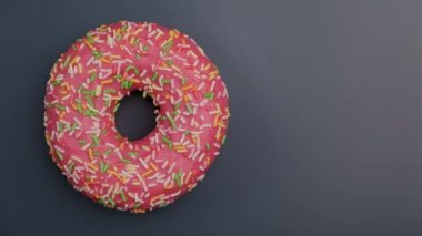 Pink donut with colorful sprinkles rotating. Colorful doughnut spinning