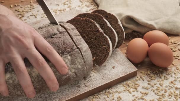 Slicing fresh bread on wooden cutting board. Slicing bread at wooden table. — Stock Video