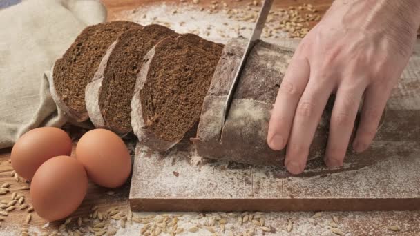 Chef slicing brown bread on wooden cutting board. — Stock Video