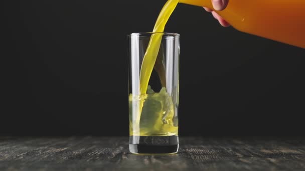 Sinaasappelsap wordt op zwarte achtergrond in glas gegoten. Concept biologische drank. — Stockvideo