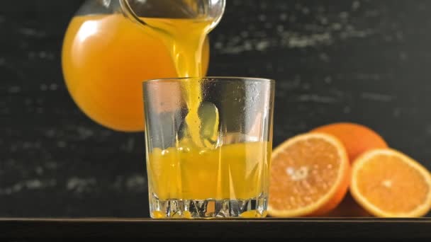 Pouring orange juice into glass with ice cubes. Yellow lemonade pouring in glass — Stock Video