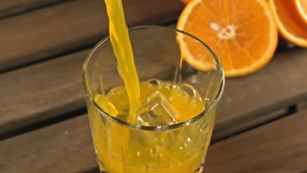 オレンジジュースは氷のキューブでガラスに注がれています。有機飲料の概念. — ストック動画