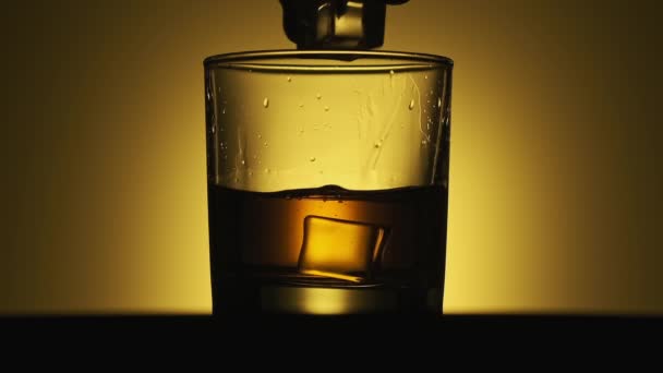 Eis fiel in Zeitlupe in ein Glas Whiskey. Nahaufnahme von Glas mit Alkohol — Stockvideo