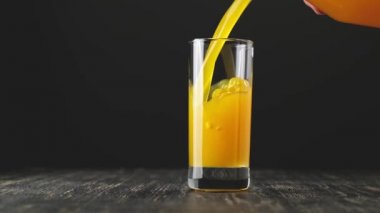 Portakal suyunu bardağa döküyorum. Camdan dökülen sarı limonata. Organik içecek.