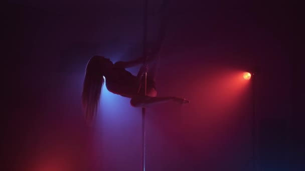 Schlanke Tänzerin im dunklen Studio mit Stange in blauem und rotem Rauch. Elegantes tanzendes Mädchen — Stockvideo