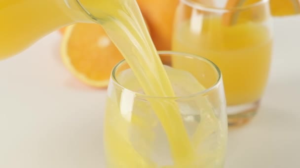 Apelsinjuice häller i glas på vit bakgrund. Koncept för ekologisk dryck. — Stockvideo