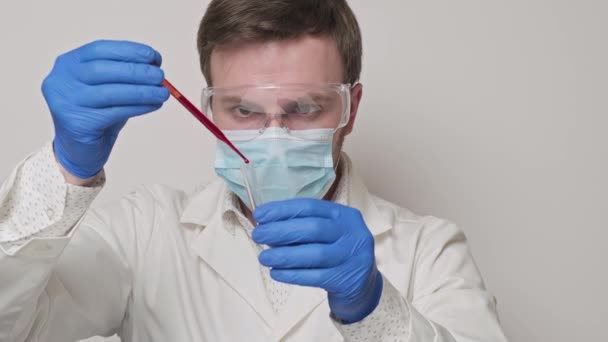 Лаборант держит пипетку и тестирует образцы крови. Крупный план в 4K, UHD — стоковое видео