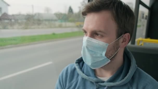 O homem monta um autocarro com máscara médica na cara. Triste cara com alergia olhando para a estrada — Vídeo de Stock