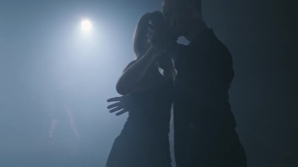 Para tańczących tango w zadymionym studio z reflektorami. Sylwetka w rozdzielczości 4K, UHD — Wideo stockowe