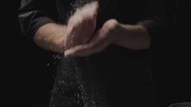 Şef un kaplı ellerini çırpıyor. Fırıncı hamur ve unla çalışıyor.