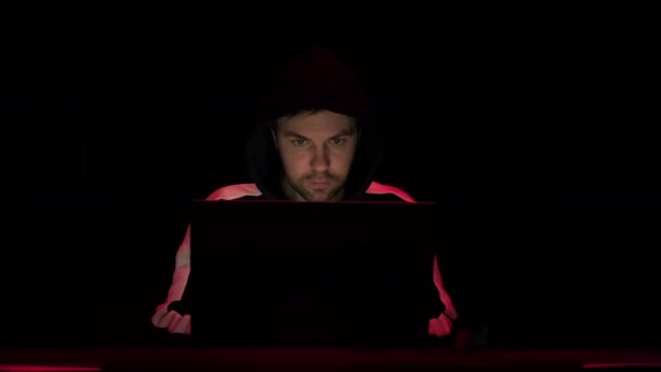 男性黑客在电脑上工作。警察的紧急信号灯映照在他身上 — 图库视频影像
