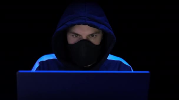 Hacker in hood and mask writing virus program for cyber attack. Police lights — Stock Video