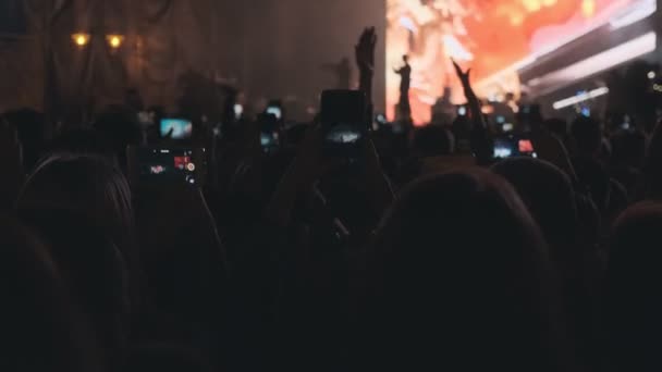 Multitud viendo un concierto musical increíble. Gente saludando manos con teléfonos inteligentes . — Vídeo de stock