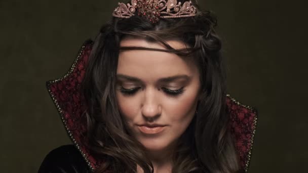Gyönyörű királynő sötét háttérrel. Nő köpenyben és koronában. 4K, UHD — Stock videók