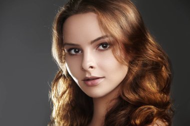 Kahverengi renk saç uçan ile güzel genç kadın modeli. Temiz Cilt kızdırma glamour moda makyaj ile güzellik portresi. Kıvırcık saç modeli yapmak. Saç bakım, makyaj. Yatay Güzellik Portresi