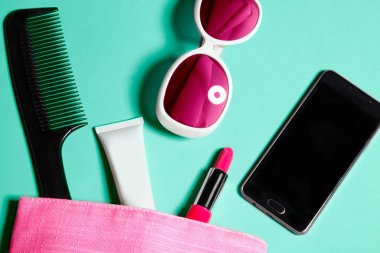 Üstten Görünüm kadın çanta malzeme. Kadın kozmetik ve Aksesuar kümesi. Glamour araçları ve güzellik nesneleri. Pembe çanta, beyaz güneş gözlüğü ve akıllı telefon