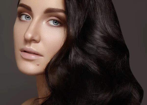 Belle jeune femme avec volume coiffure bouclée. Portrait de beauté du modèle brune avec peau propre, maquillage de mode miroitant. Maquillage, coiffure. Soins capillaires, maquillage. Portrait beauté — Photo