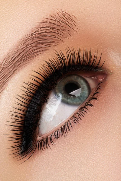 Foto de perto dos olhos femininos. Mulher appling forro olho preto. Maquiagem de moda com forma de setas perfeitas com cores brilhantes de sombras aquamarinas. Cosméticos e maquiagem — Fotografia de Stock