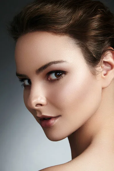 Belle jeune femme au visage propre, à la peau brillante, au maquillage naturel mode, aux sourcils de perfection. Jolie coiffure de chignon. Portrait spa, cosmétiques naturels, look frais et sain — Photo