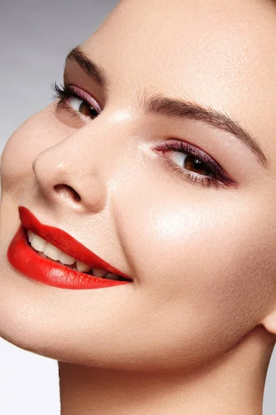 Hermosa modelo con maquillaje de moda. Retrato de cerca mujer sexy con glamour maquillaje brillo labial y maquillaje delineador de ojos negro. Tiro de celebrar el rostro, piel limpia, labios con lápiz labial rojo, cejas —  Fotos de Stock