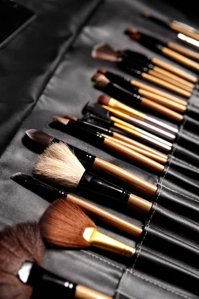 Set de pinceaux de maquillage dans un sac de maquillage noir. Outils de beauté pour visage professionnel. Brosses pour maskara, fards à paupières, fond de teint, rouge à lèvres, blush et crème pour le visage — Photo