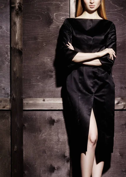 Modeporträt der schönen jungen Frau in sexy schwarzen Kleid in der Nähe mit Holzwand. eleganter dunkler Abendlook. — Stockfoto