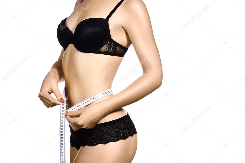 Fitness body with a measurement tape. Beautiful athletic slim woman measuring her waist by measure tape.