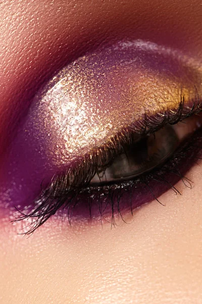 Primer plano ojo femenino con hermosa moda brillante maquillaje. Hermoso oro brillante, sombra de ojos púrpura, brillo húmedo — Foto de Stock