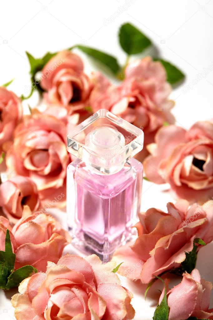 Perfume bottle in pink flower roses. Spring background with luxury aroma parfume. Beauty cosmetic shot