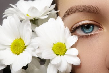 Güzel mavi kadın göz beyaz bahar çiçek ile. Temiz cilt, moda doğal makyaj. İyi vizyon, sağlık