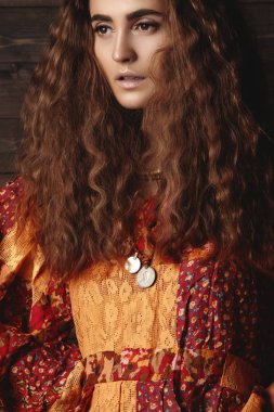 Uzun kıvırcık saç modeli, moda takı esmer saçlı güzel genç kadın. Hint tarzı kıyafetler, uzun elbise