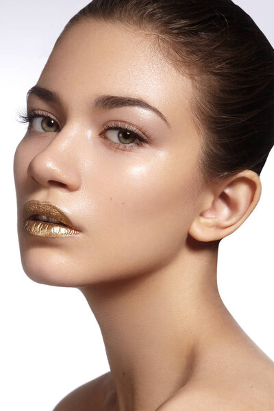Young Beautiful Woman with clean soft Skin, bright gold Lips Makeup. Perfect eyebrows shapes. Day make-up