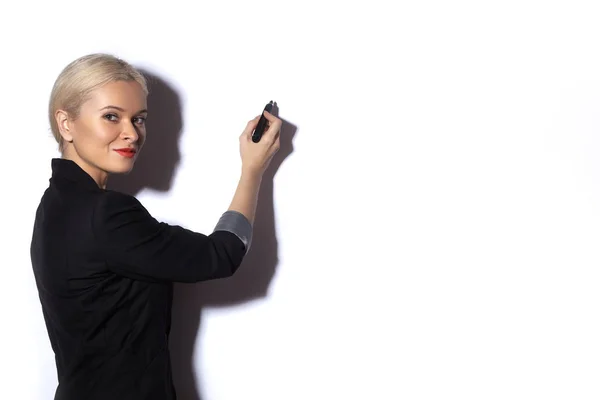 Geschäftsfrau schreibt Notizen auf eine Spiegeltafel. Büromode. Blonde Modellpräsentation mit Filzstift auf Weiß — Stockfoto