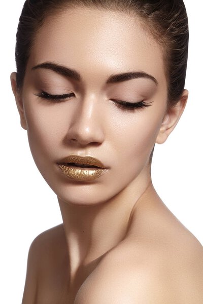 Портрет крупным планом с прекрасным женским лицом. Золотой цвет моды макияж губ, чистая блестящая кожа и блеск для губ

