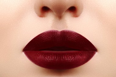Glamour dudaklar duygusallık hareketi ile. Koyu kırmızı ruj, temiz cilt. Velvet mat makyaj. Dolgu ile büyütme