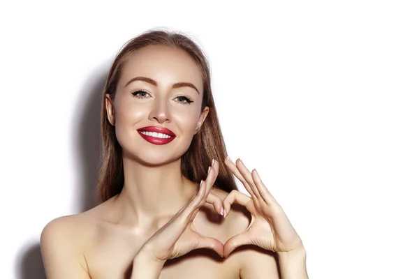 Mujer joven romántica haciendo forma de corazón con sus dedos. Símbolo de amor y San Valentín. Chica de moda con sonrisa feliz — Foto de Stock