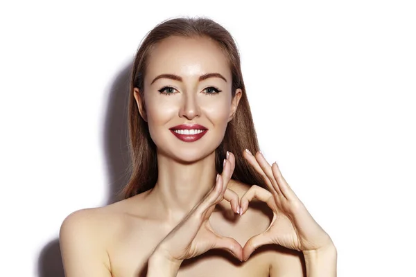 Mujer joven romántica haciendo forma de corazón con sus dedos. Símbolo de amor y San Valentín. Chica de moda con sonrisa feliz — Foto de Stock
