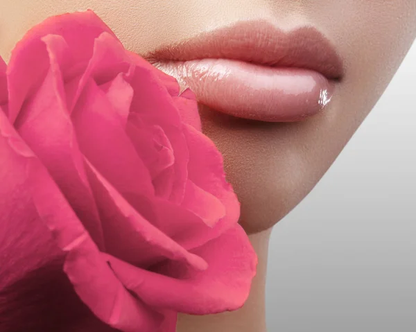 Labios con maquillaje brillante de brillo de labios. Piel limpia perfecta, maquillaje labial fresco. Hermoso spa con tierna rosa rosa flor —  Fotos de Stock